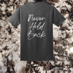 The back of a dark heather grey t-shirt displaying the 'Never Hold Back' quote in an elegant white script.